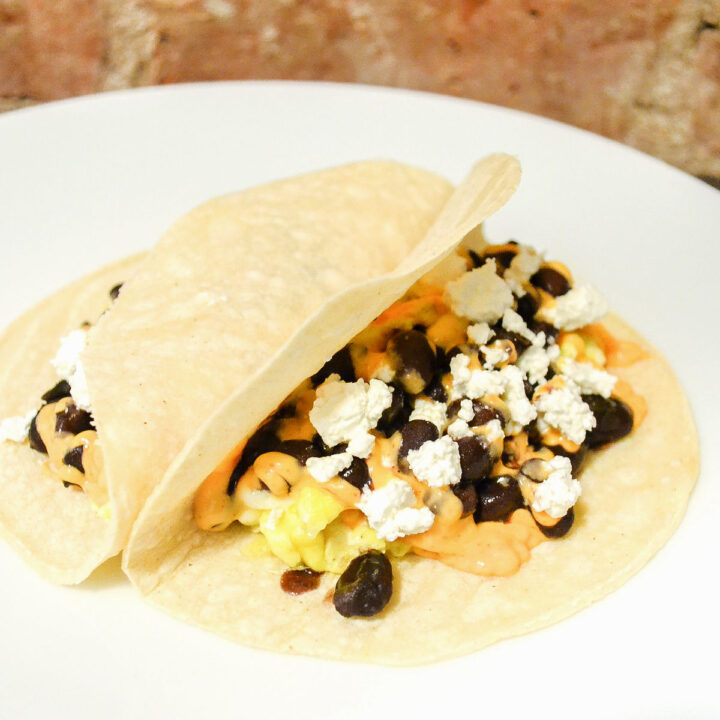 Two black bean breakfast tacos on a white plate.
