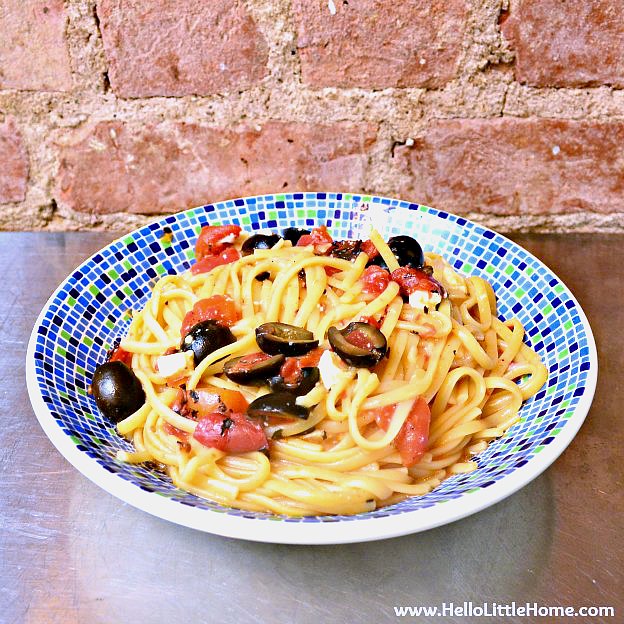 A bowl of one pot pasta with tomatoes, olives, and feta.