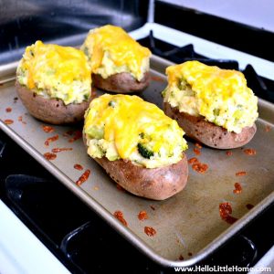Four loaded stuffed Twice Baked Potatoes with melted cheddar cheese on a baking sheet.