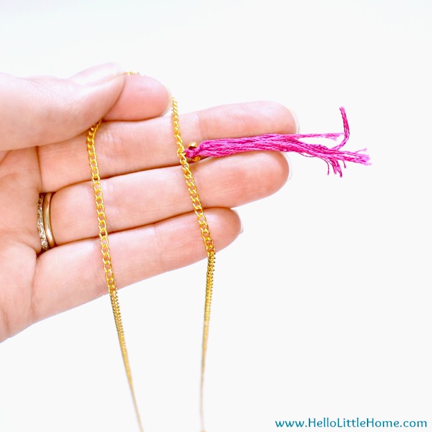A tassel attached to a necklace with a crimp bead.