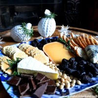 A cheese tray with cheese, chocolate, dried fruit, nuts, and more.