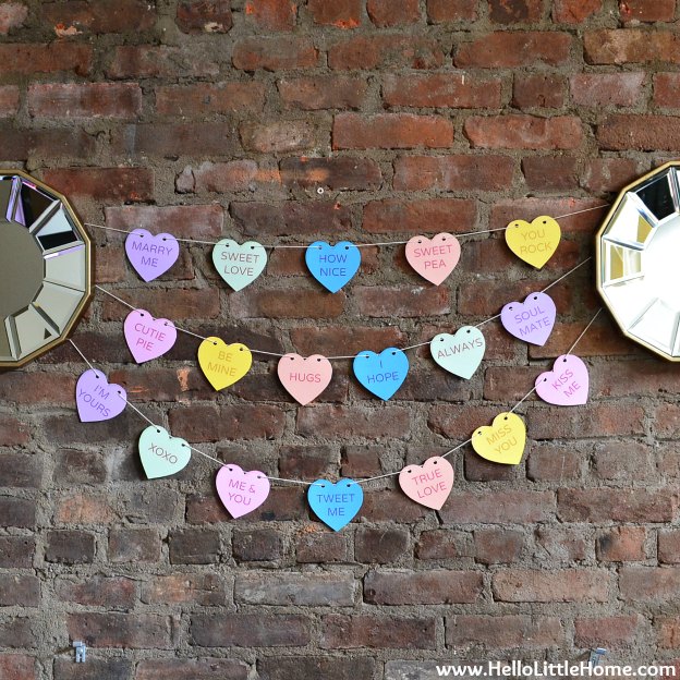 A Conversation Heart Banner strung between two mirrors on a brick wall.