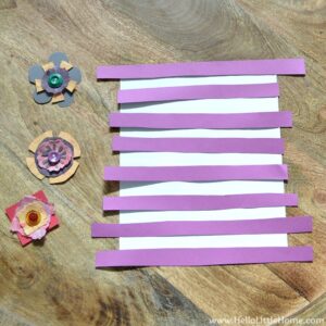 A piece of white paper with purple paper strips arranged on top.