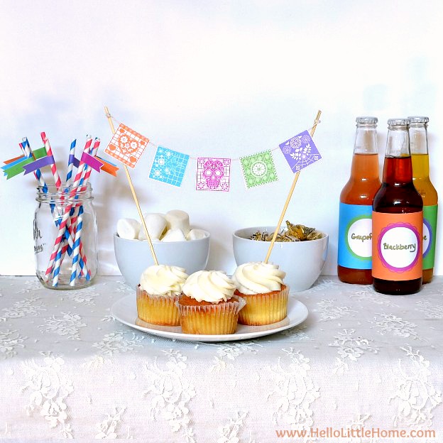 A table topped with cupcakes, sodas, and straws.