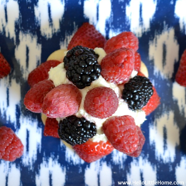 An overhead photo of a berry topped tart on a blue patterned tray.