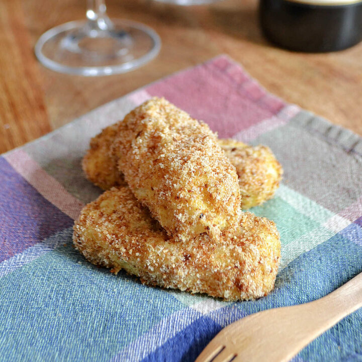 Three Potato Croquettes served on a plaid napkin with a fork.