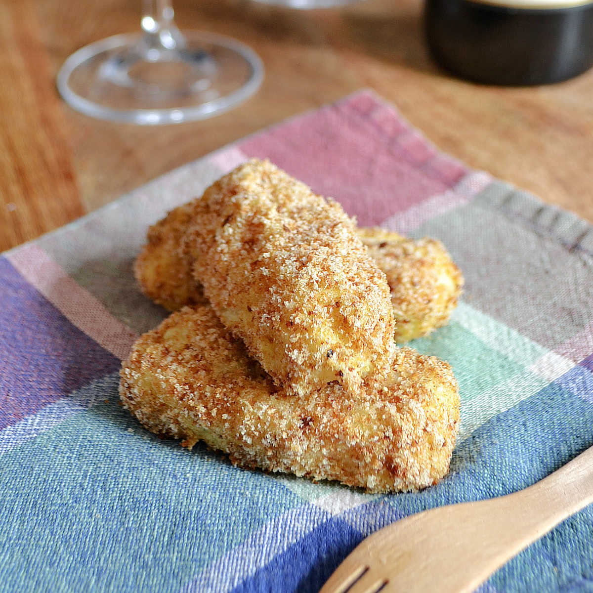 Three Potato Croquettes served on a plaid napkin with a fork.