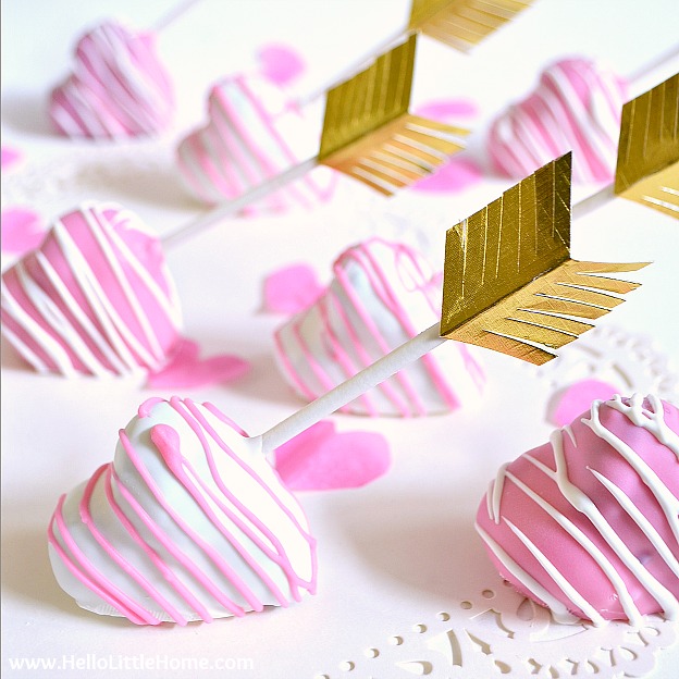 Pink and white heart shaped cake pops on a white doily.