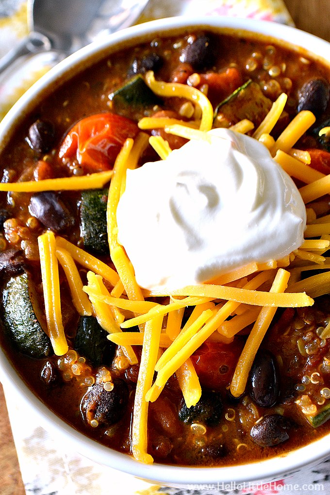 Closeup of a bowl of vegan Quinoa Chili topped with sour cream and cheese.