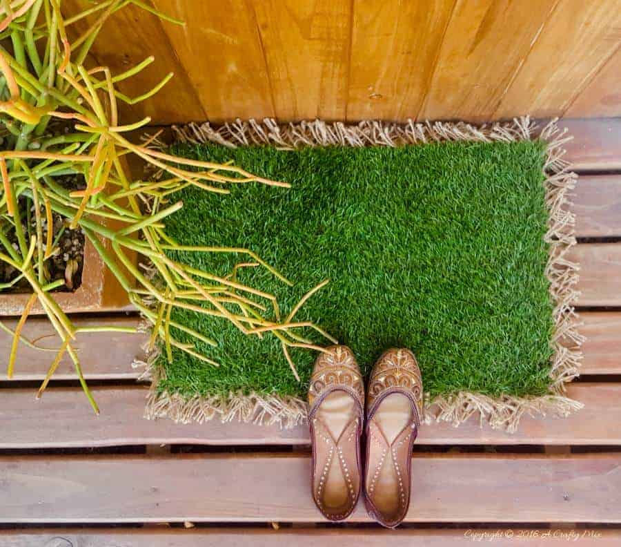 An astro turf doormat topped with a pair of shoes.