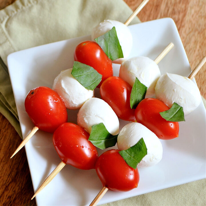 Three Caprese Skewers on a white plate.