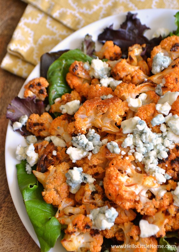 These Spicy Buffalo Cauliflower Bites make a delicious appetizer or snack! Make this spicy recipe with roasted cauliflower tossed with homemade buffalo sauce and topped with blue cheese! This Buffalo Cauliflower recipe is the perfect snack or vegetarian appetizer for any party! | Hello Little Home #buffalosauce #cauliflower #buffalocauliflower #gameday #appetizer #snackrecipe #vegetarian #vegetarianrecipes #partyfood