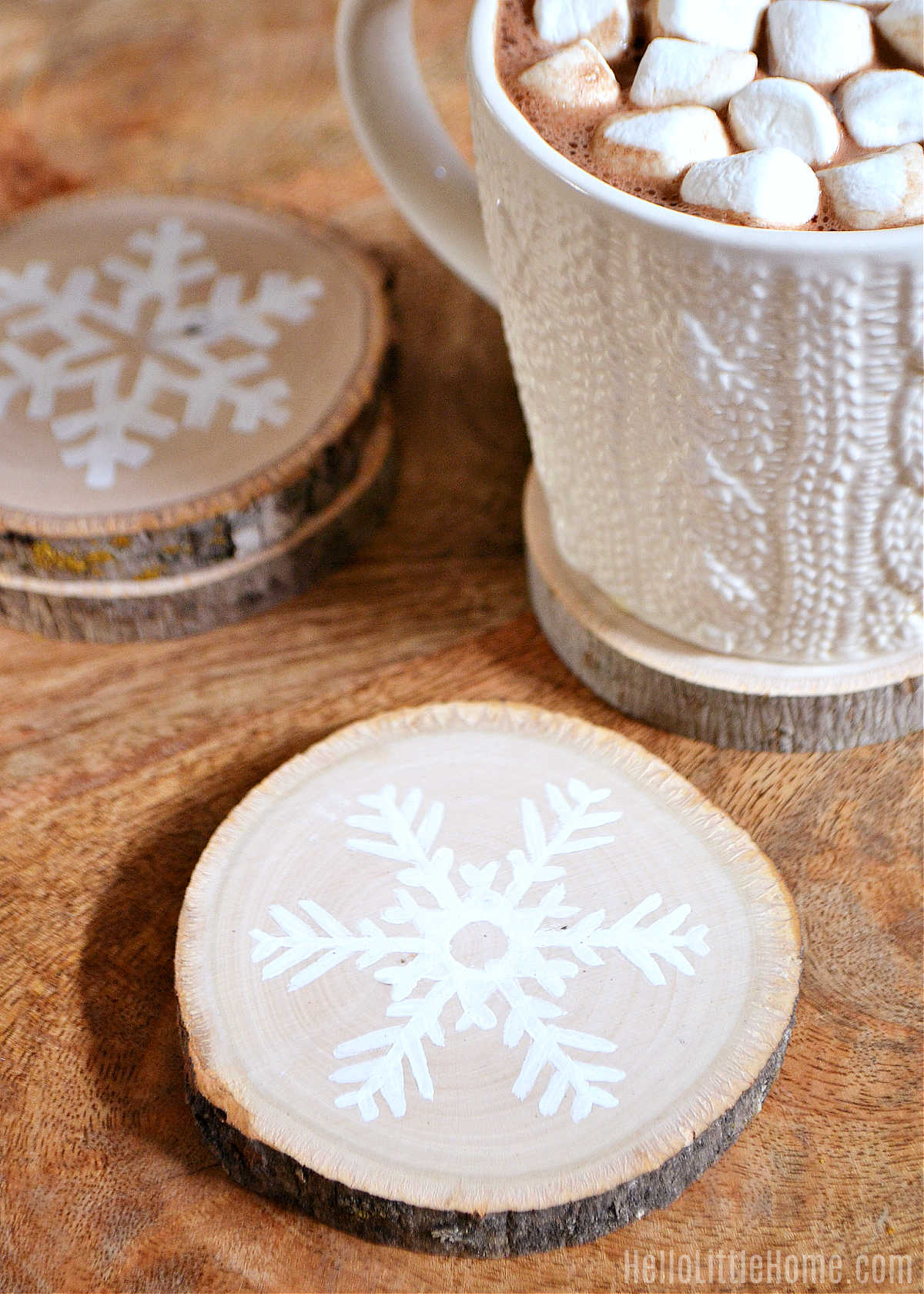 The finished coasters on a wood table next to a mug of hot chocolate.