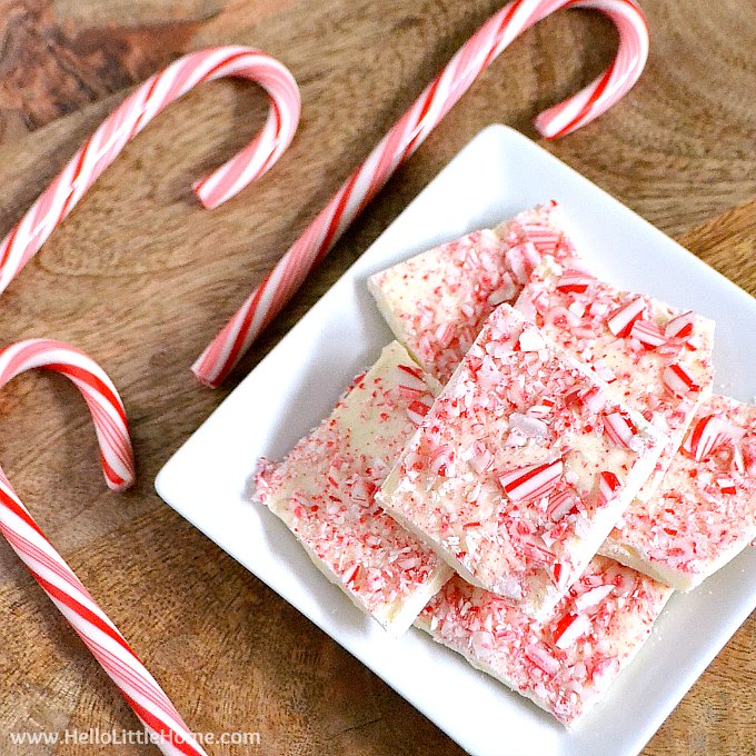 A plate of Peppermint Bark and three candy canes on a wood table.