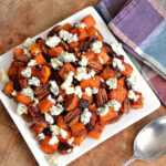Roasted Butternut Squash with Cranberries, Pecans, and Blue Cheese on a white plate.