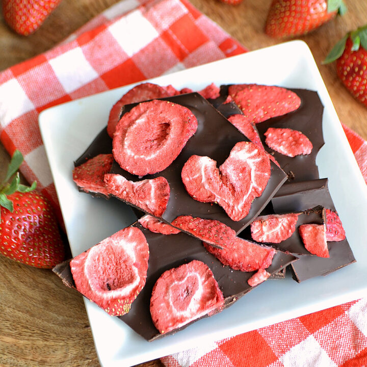 A plate of Strawberry Bark, strawberries, and a checked napkin on a wood table.