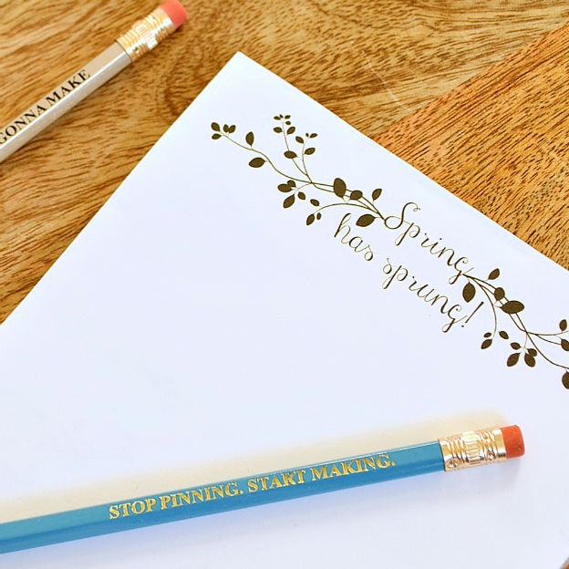 A printable notepad and two pencils on a wood table.
