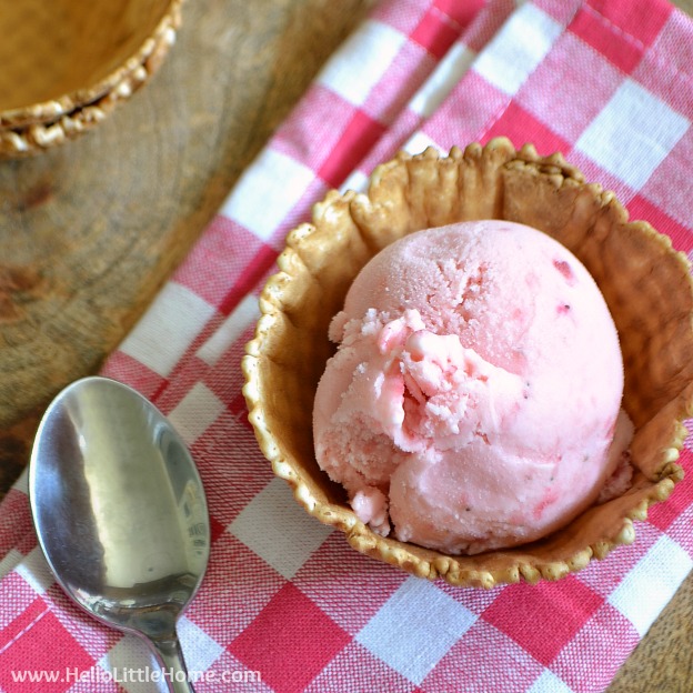 A scoop of Strawberry Frozen Yogurt in a waffle cup on a checked napkin.