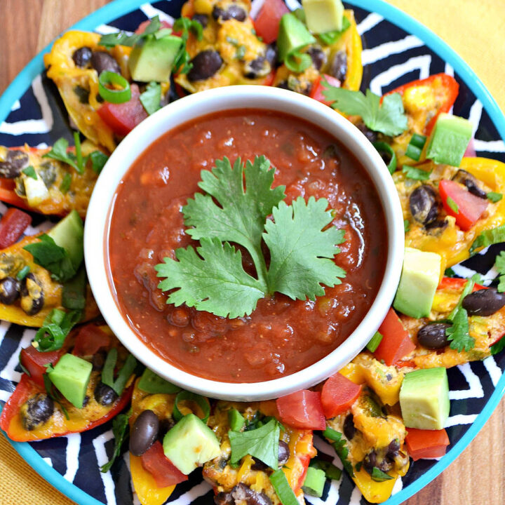 Bell Pepper Nachos served with a bowl of salsa on a round tray.