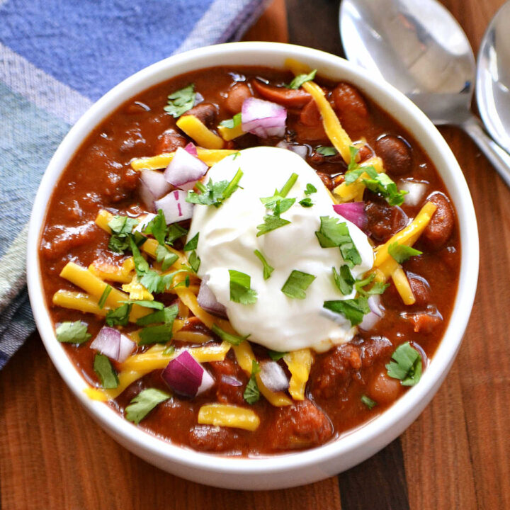 3 Bean Chili (made in a slow cooker) served in a white bowl with toppings.