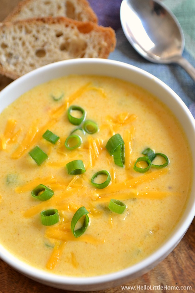 Closeup of a bowl of beer cheese soup with bread and a spoon in the background.