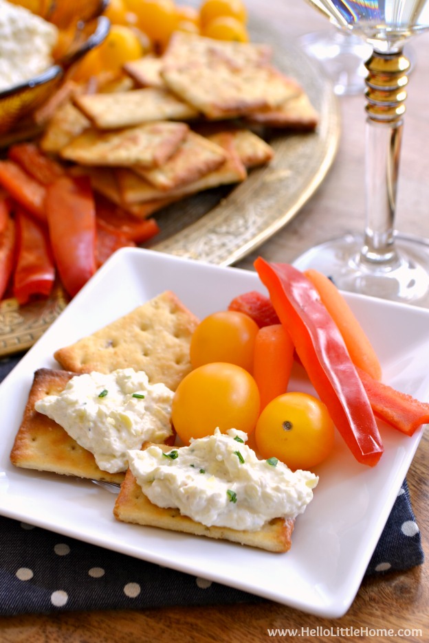 A small plate topped with crackers, spread, and fresh veggies.