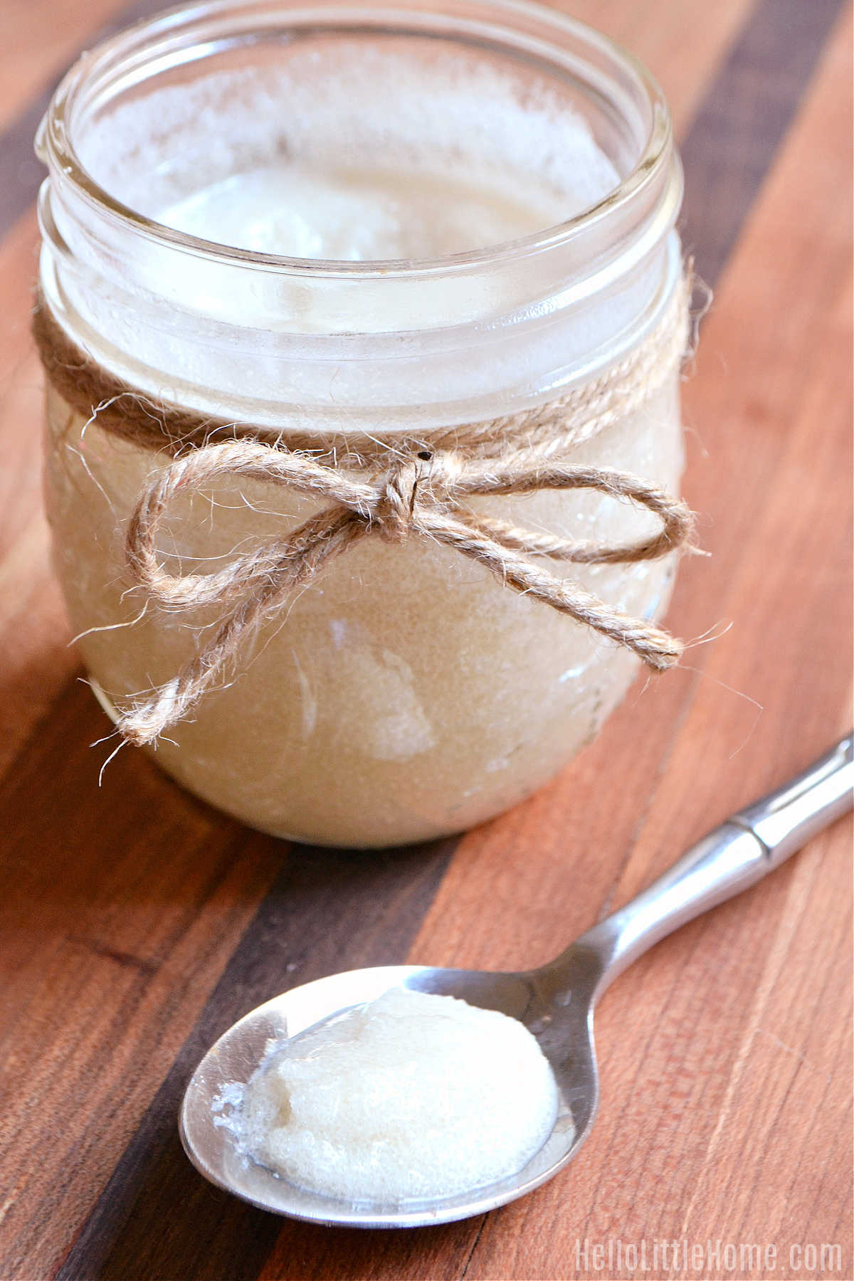 A spoonful of scrub in front of a jar on a wood board.
