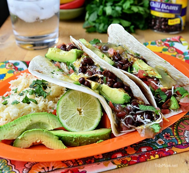 Avocado and black bean tacos on an orange plate.