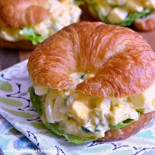 Deviled Egg Salad served on a croissant and placed on a blue and green napkin.