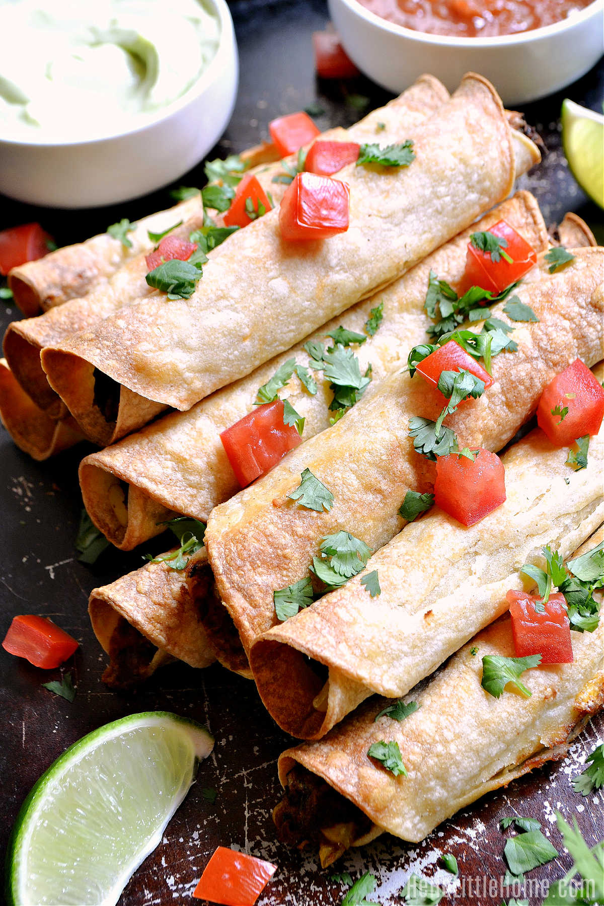 The finished veggie taquitos on a table with toppings and sauces.