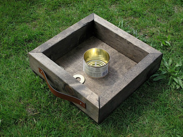 A DIY washer toss game sitting on grass.