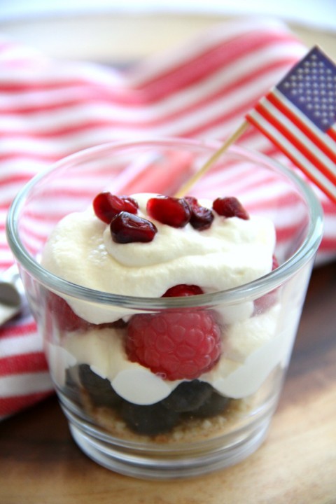 A parfait served in a glass bowl with a striped napkin and small flag in the background.