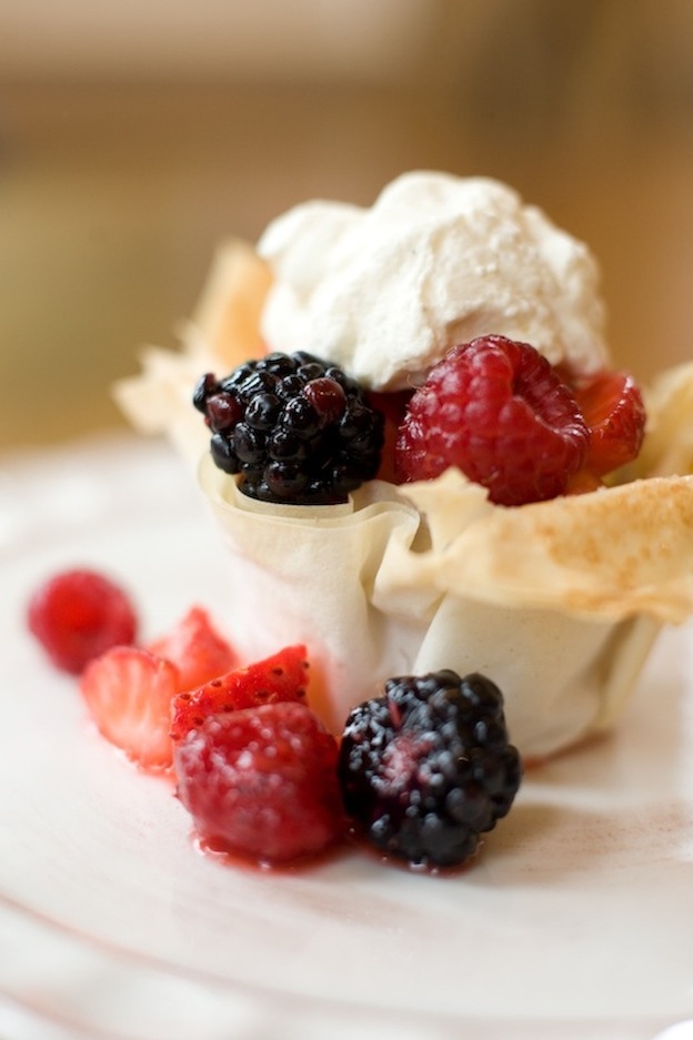 A small tart served on a white plate with berries.