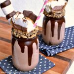 Two S'mores Freakshakes on a wood cutting board.
