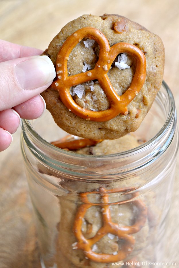 A hand holding a Salted Caramel Pretzel Cookie above a jar.
