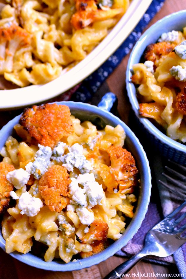 Two bowls of Buffalo Cauliflower Mac and Cheese on a wood table.