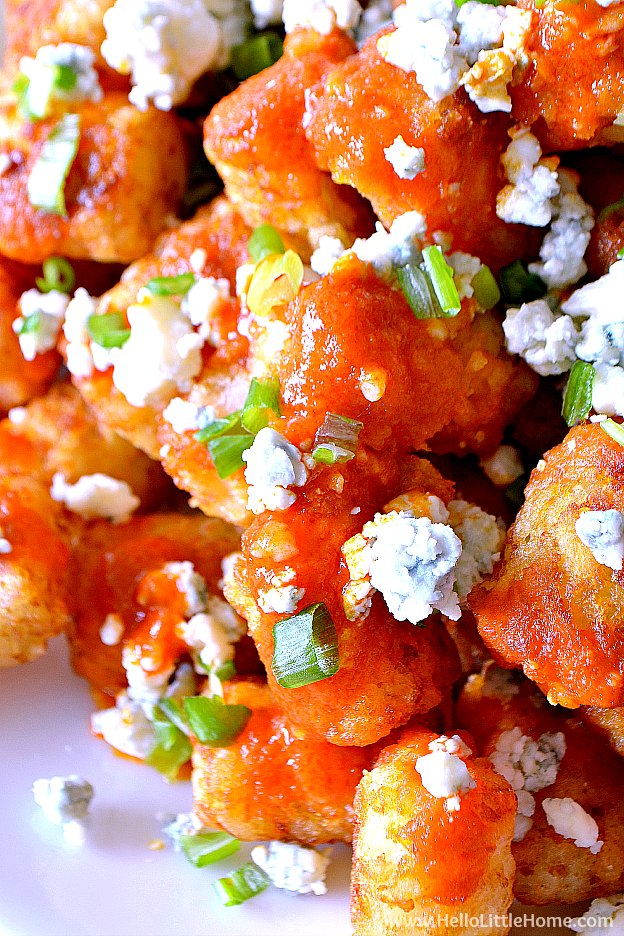Close up of Easy Buffalo Tatchos (Tater Tot Nachos) ... a fun and easy game day recipe! These easy vegetarian tater tot nachos are loaded with a spicy homemade buffalo sauce, creamy blue cheese, and fresh green onions. Makes a great appetizer for game day parties or a yummy snack any day! | Hello Little Home