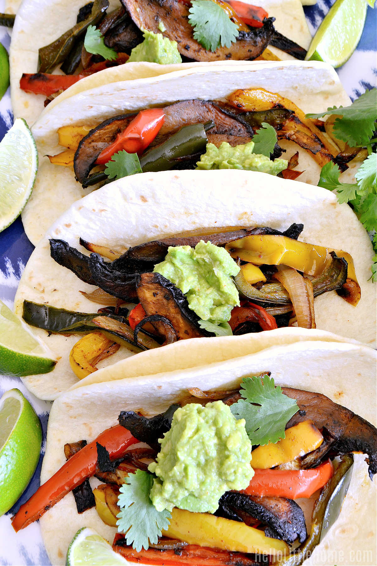 A row of tortillas filled with the cooked veggies and topped with guacamole.