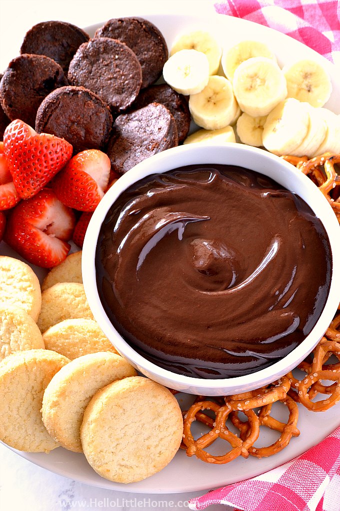 Easy Chocolate Fondue surrounded by brownies, strawberries, cookies, and more for dipping.