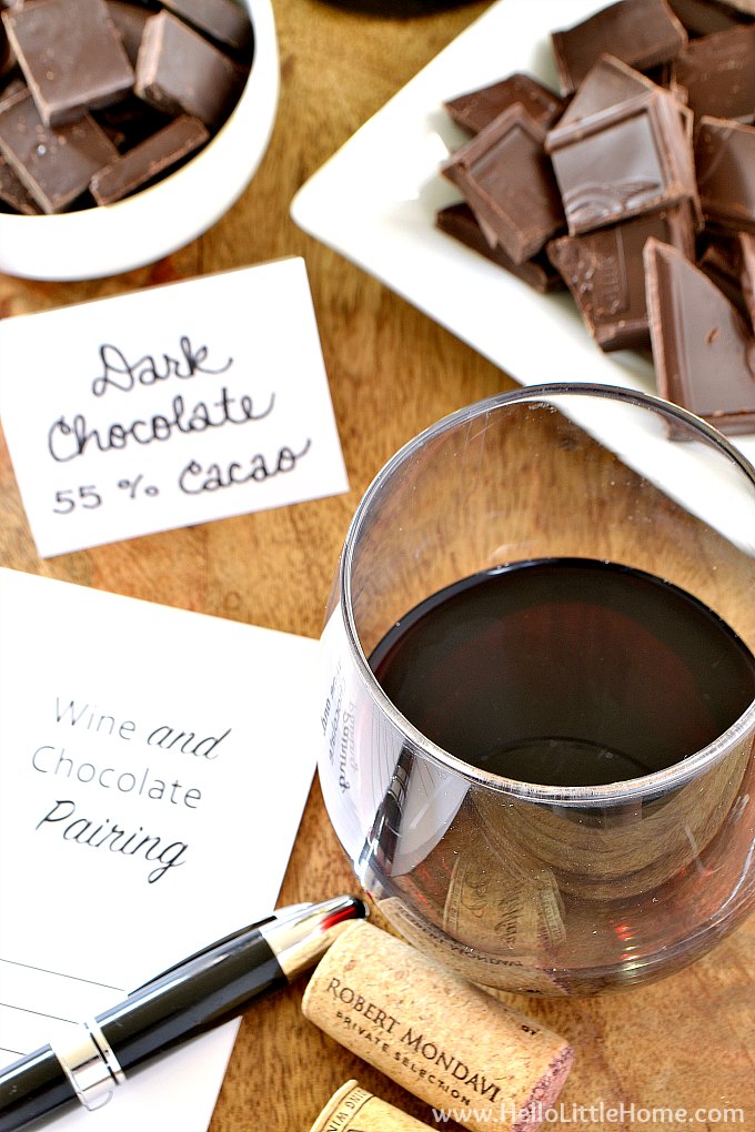A glass of red wine, wine corks, and a wine and chocolate pairing card.