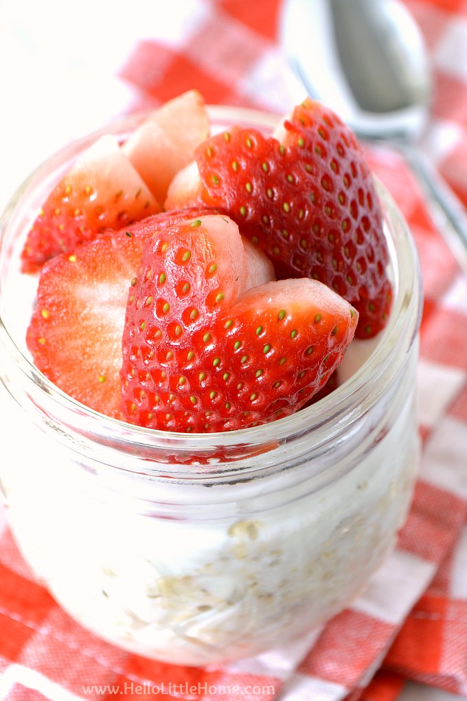 A mason jar filled with Strawberry Overnight Oats on a red checkered napkin.