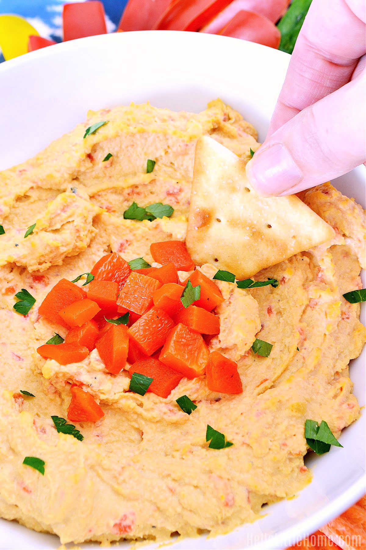 A hand dipping a chip in the finished dip.