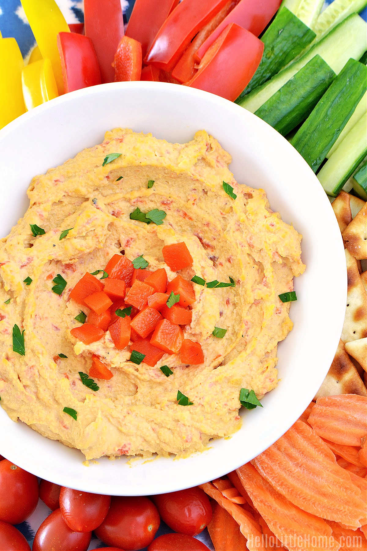 A bowl of Roasted Red Pepper Hummus surrounded by veggies.