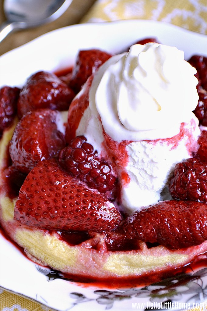 A waffle topped with mixed fruit sauce and ice cream.