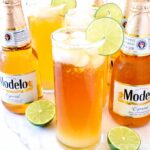 Three Cheladas and a few bottles of Modelo on a marble counter.