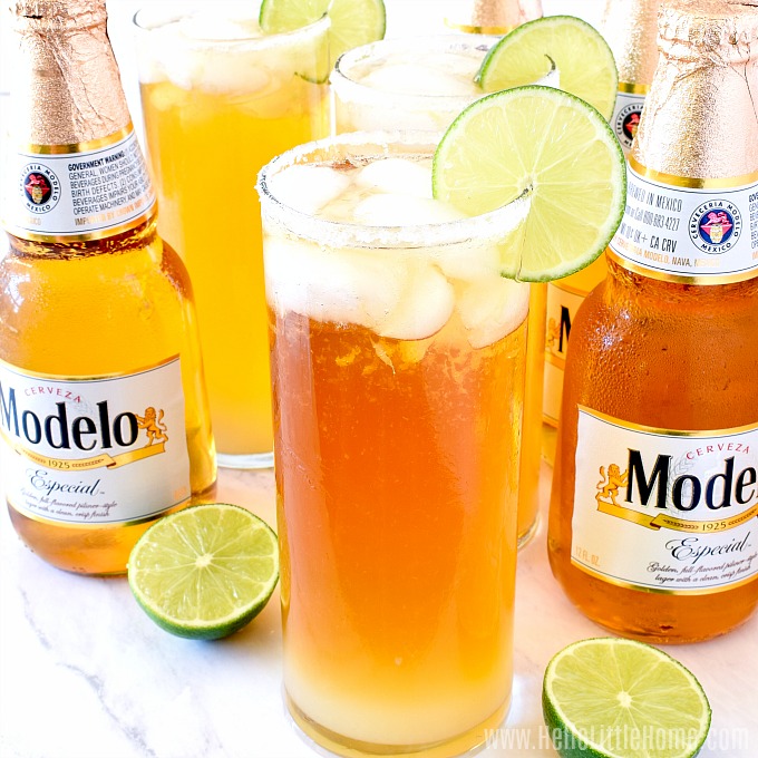 Three Cheladas and a few bottles of Modelo on a marble counter.
