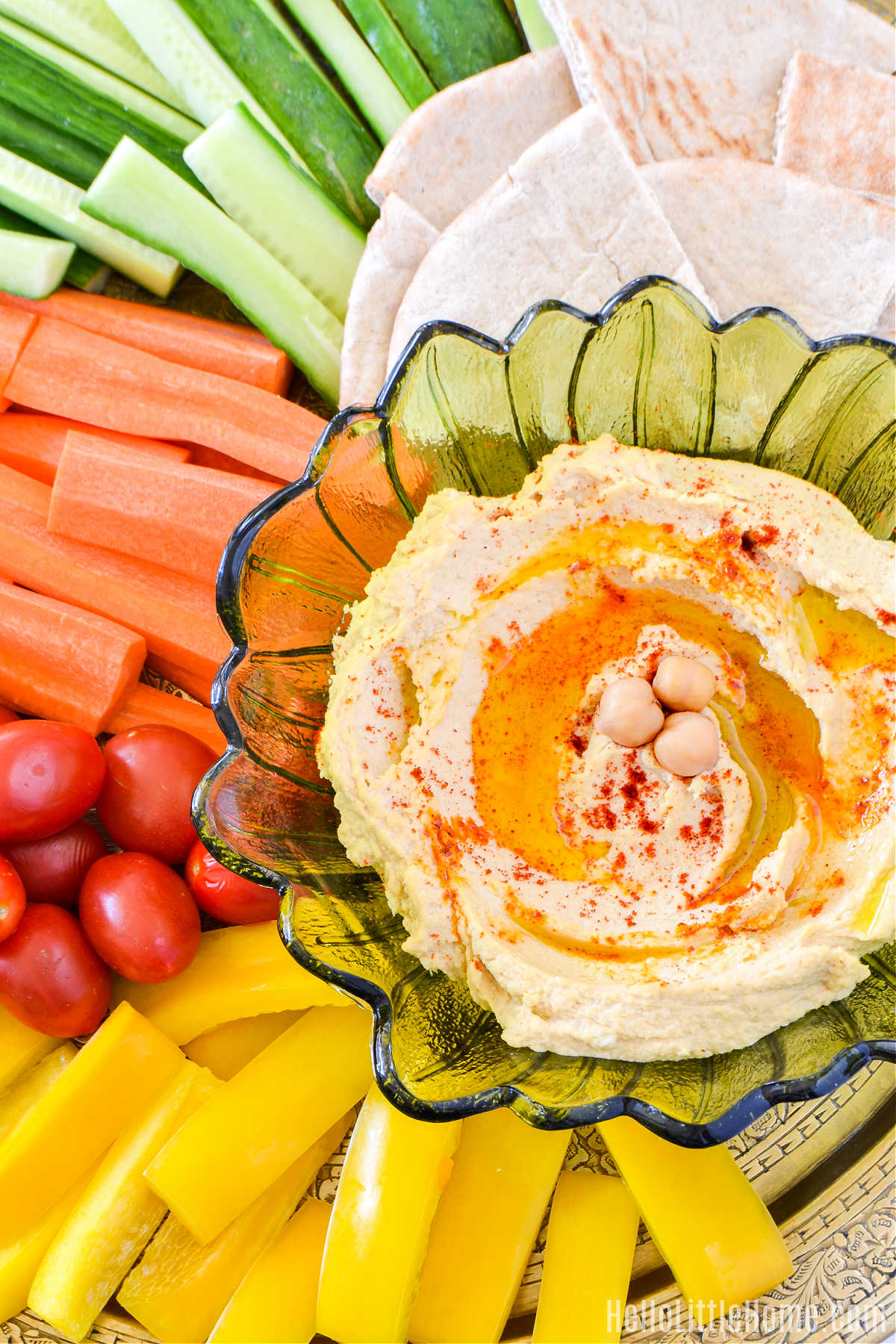 A bowl of the finished dip on a platter surrounded by veggies and pita bread.
