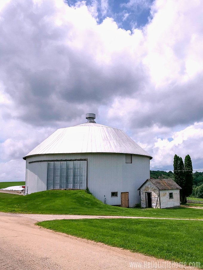 A white round barn surrounded by grass.