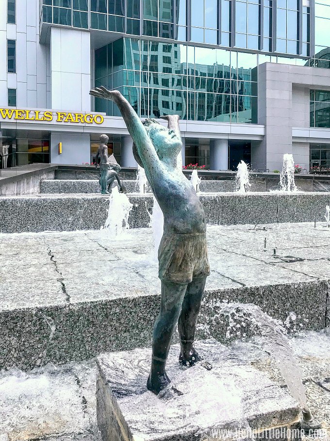 A statue of a girl with her arms raised at the Wells Fargo Plaza Fountain in Uptown Charlotte.