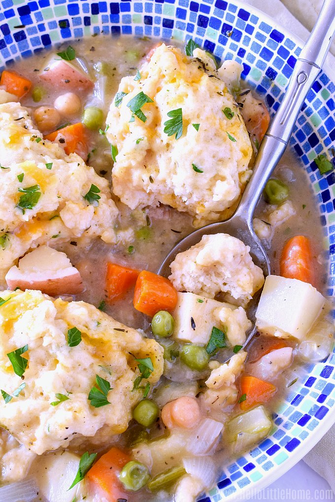 A bowl of Vegetable Stew and Dumplings with a spoon in it.